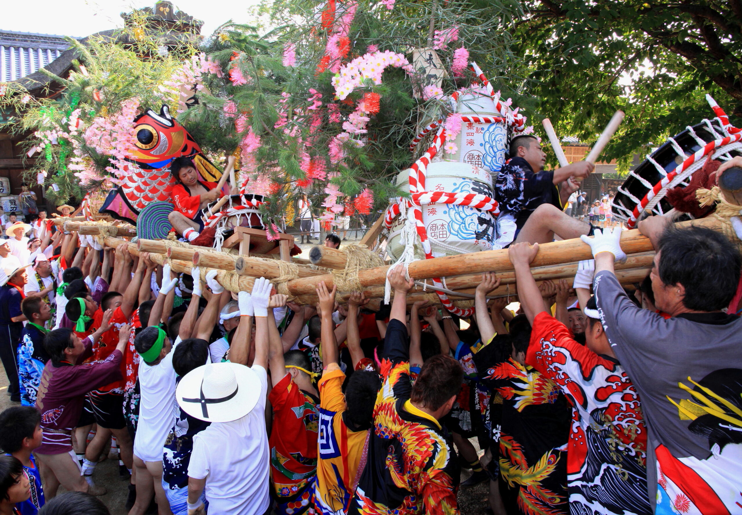 Crowd carries a decorated festival float featuring a dragon, flowers, and lanterns at a parade world festival scene